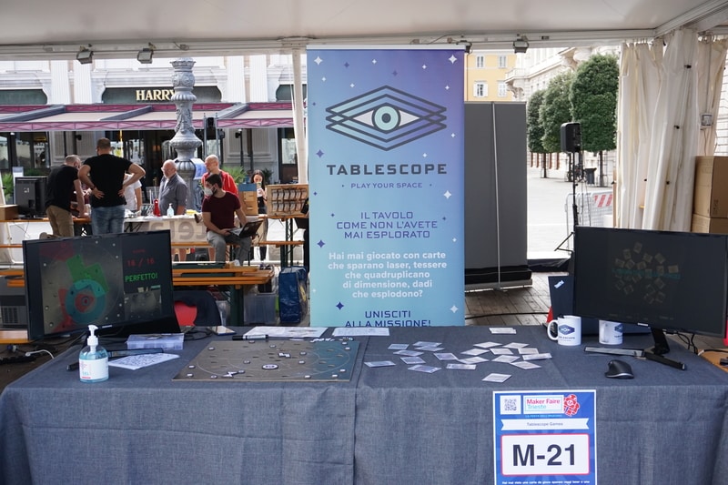 Two tables in an outdoor pavilion with screens and board games on them